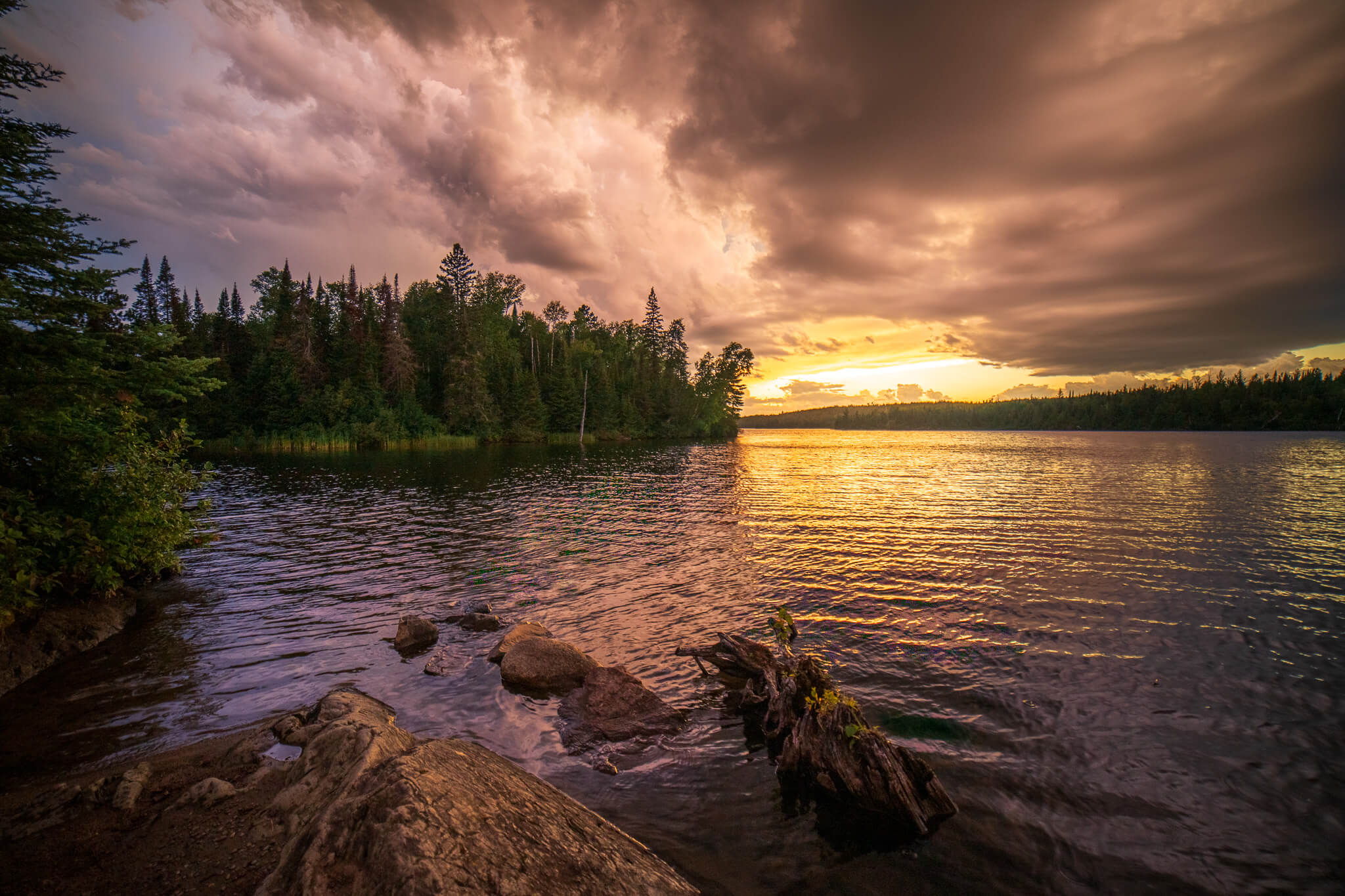 Dramatic stormy golden sunset over wilderness lake with rocky shore, Boundary Waters Minnesota