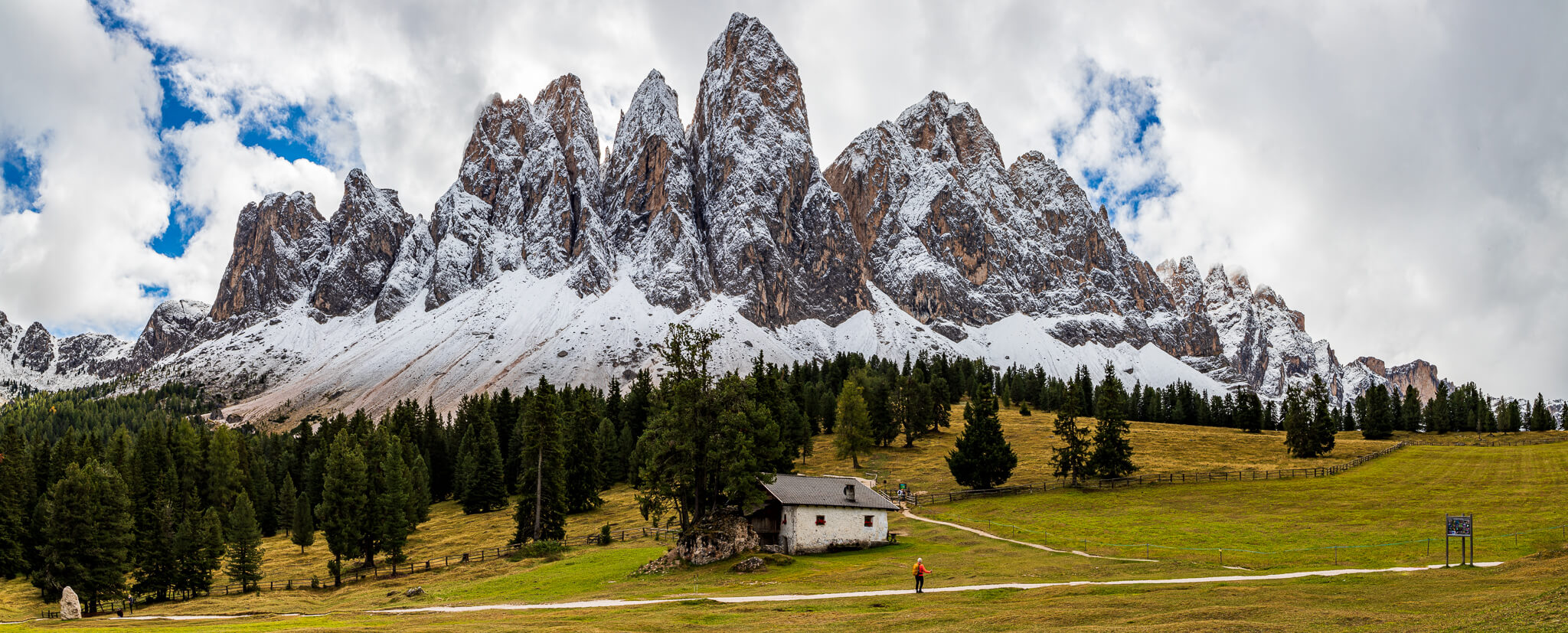 Odle peaks panorama with farmhouse and hiker