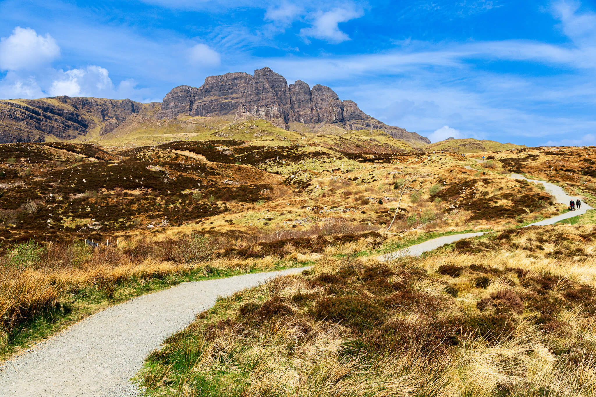Trail winding through golden moorland toward the Old Man of Storr rock formation, Isle of Skye