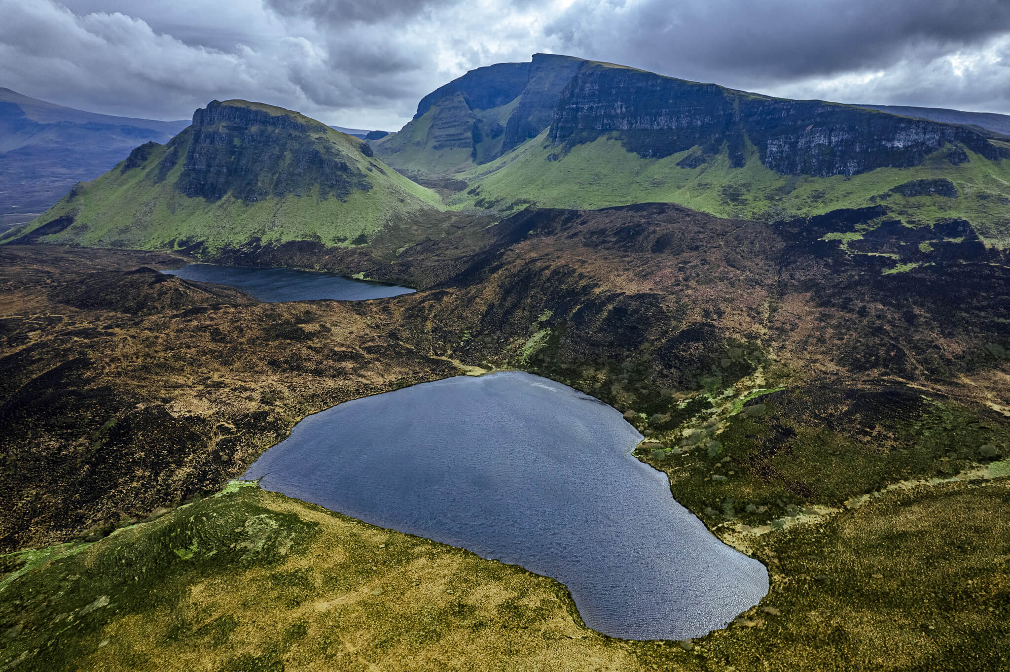 Aerial panorama of twin lochs amid moorland below Quiraing escarpment, Isle of Skye