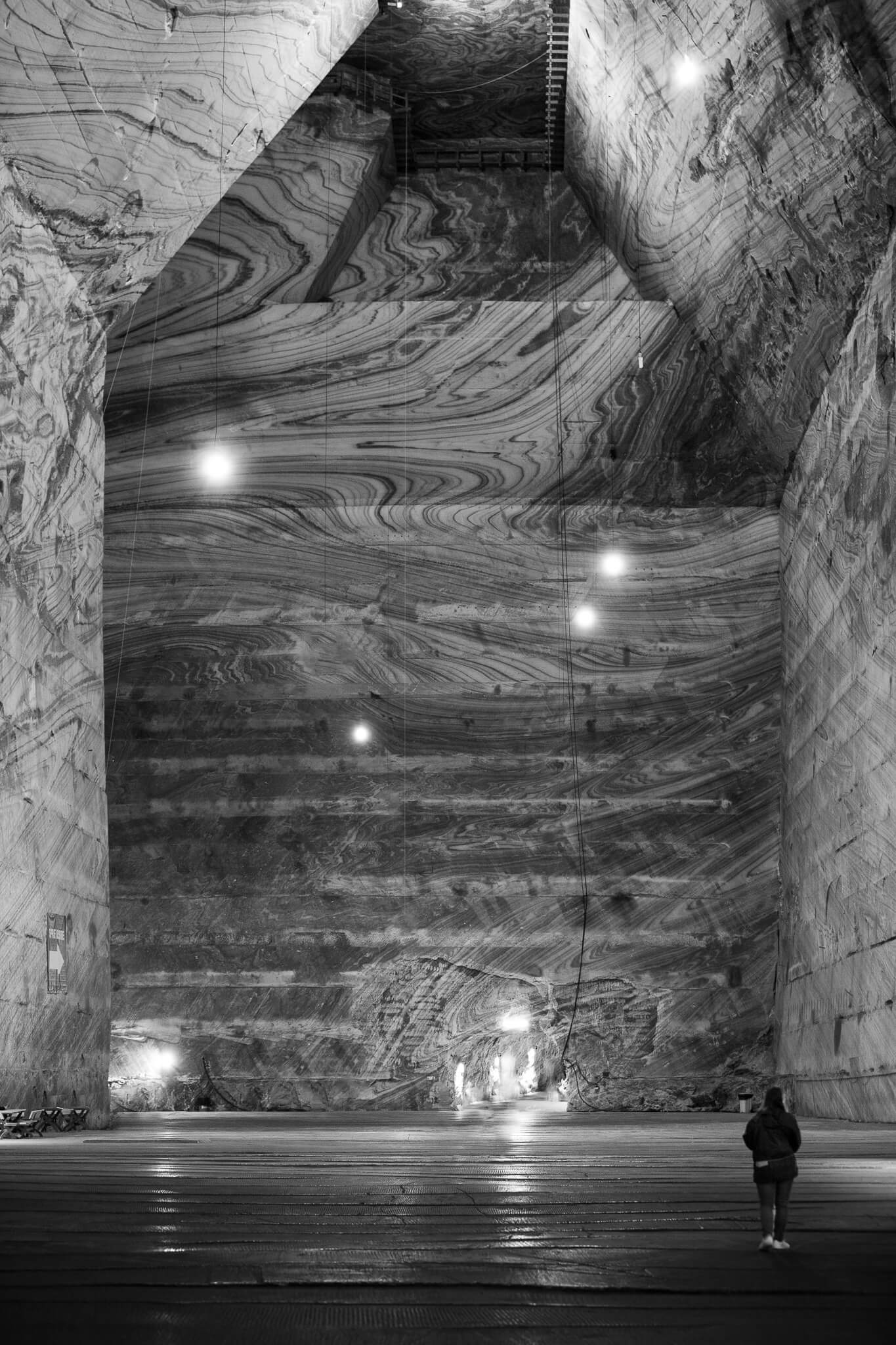 Black and white interior of vast Turda Salt Mine with lone figure, Romania
